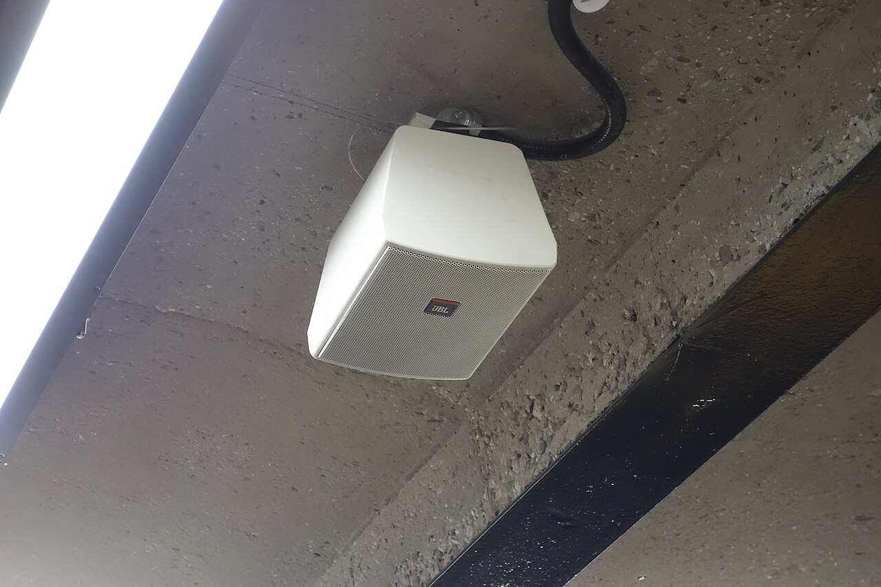 Haut-parleur blanc fixé sous le plafond en béton d'une station de métro