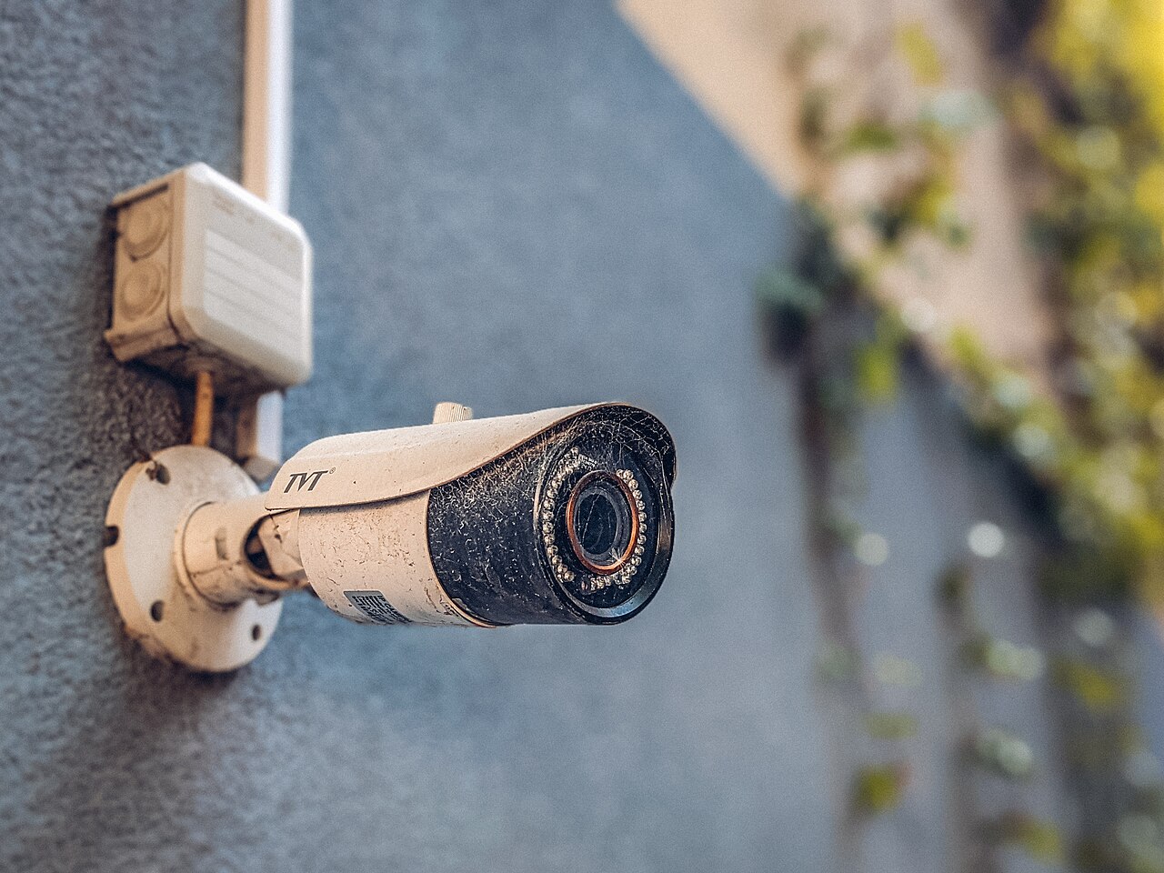 Caméra de vidéoprotection tubulaire fixée sur un mur de façade, à côté de son boîtier de raccordement